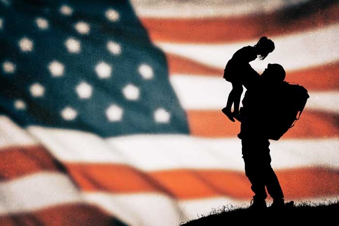 U.S. soldier holding child with American flag backdrop