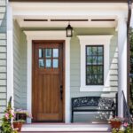 Wooden front door with white trim on a light green house in Portland OR